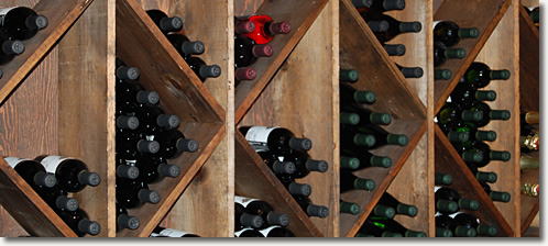 Dozens of wine bottles placed in a wall-mounted wooden wine rack